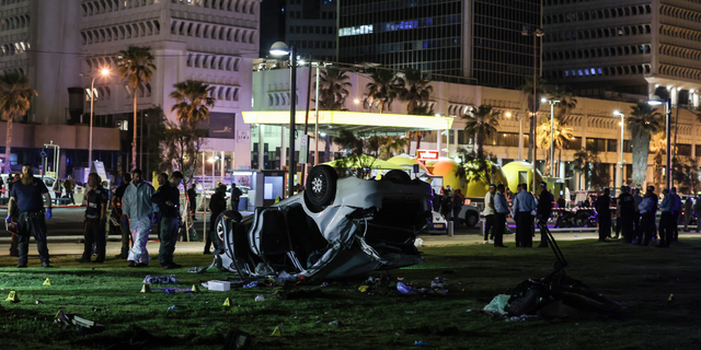 Police and forensic officers work at the site after a driver rammed passers-by with his car before flipping over.Â