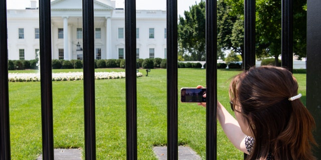 Tourists visit the fence line on the north side of the White House