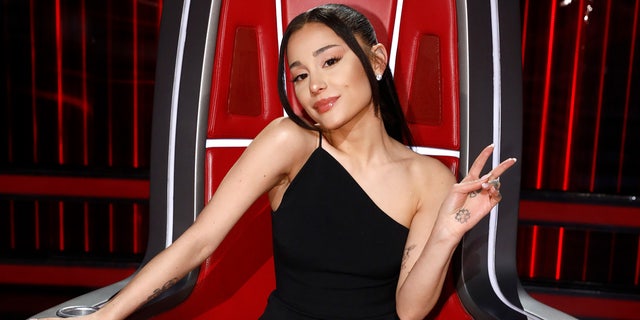 Ariana Grande flashes a peace sign while judging The Voice