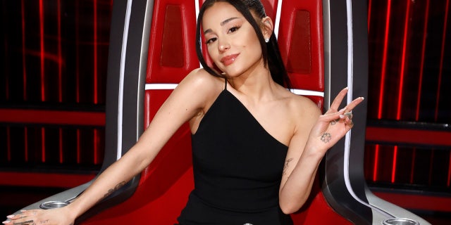 Ariana Grande flashes a peace sign while judging The Voice