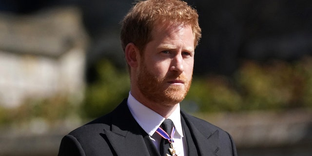Prince Harry wearing a suit and tie with medals