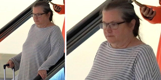 Actress Bridget Fonda wears grey shirt with stripes and carries luggage through terminal in Los Angeles