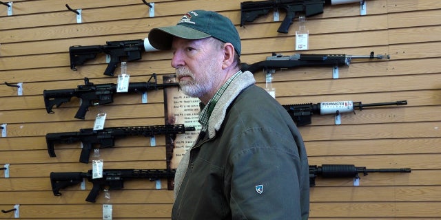 Gun store manager Bruce Smith, wall of rifles behind him