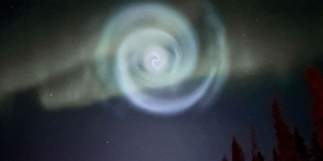 A light baby blue spiral resembling a galaxy emerges during Alaska’s aurora near Fairbanks on April 15, 2023. 