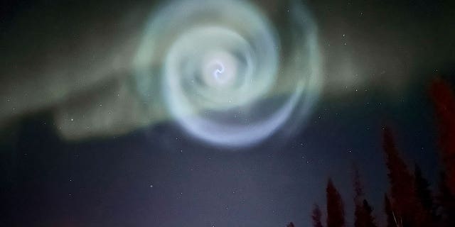 A light baby blue spiral resembling a galaxy emerges during Alaska’s aurora near Fairbanks on April 15, 2023.