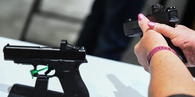 woman holds handgun at display case