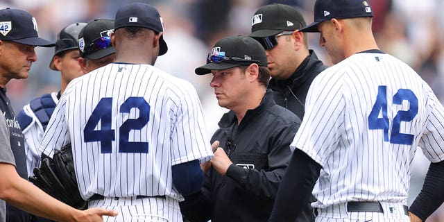 Umpire DJ Reyburn, #17, passes New York Yankees Domingo Germán in the fourth inning during a game against the Minnesota Twins at Yankee Stadium on April 15, 2023 in Bronx, New York.  All players wear the number 42 in honor of Jackie Robinson Day. 