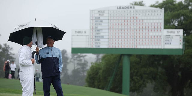Fred Couples of the United States watches from the 18th green with his caddy, George Downing, during the continuation of the weather-delayed second round of the 2023 Masters Tournament at Augusta National Golf Club on April 8, 2023 in Augusta, Georgia . 