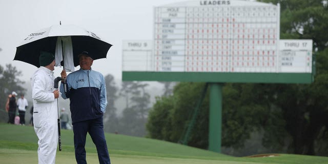 Fred Couples of the United States looks on from the 18th green with his caddie, George Downing, during the continuation of the weather-delayed second round of the 2023 Masters Tournament at Augusta National Golf Club on April 8, 2023, in Augusta, Georgia.