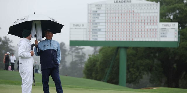 Fred Couples of the United States watches from the 18th green with his caddy, George Downing, during the continuation of the weather-delayed second round of the 2023 Masters Tournament at Augusta National Golf Club on April 8, 2023 in Augusta, Georgia . 