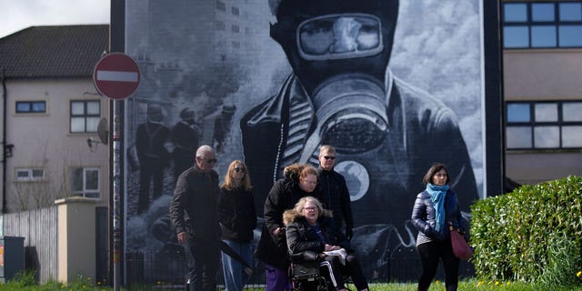 Los turistas pasan junto a un mural en la esquina de Londonderry, Derry en Irlanda del Norte.  El primer ministro británico conservador, Rishi Sunak, rindió homenaje el lunes a los políticos de Irlanda del Norte que negociaron el Acuerdo del Viernes Santo de 1998 e instó a los políticos en ejercicio a volver al trabajo.