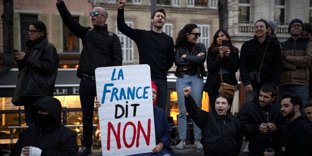 A woman holds a sign reading "France says no" during a demonstration in Marseille, southern France, on March 16, 2023. French protestors are opposing the government’s proposal to raise the retirement age from 62 to 64.