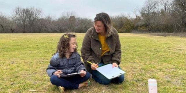 A parent teaches a child outside in nature at a Barefoot University class. The home-school forest school has grown to over 3,000 kids participating across six states. 