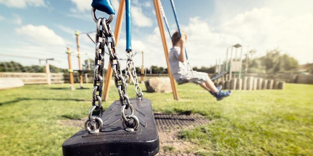 Boy sits alone on park swing