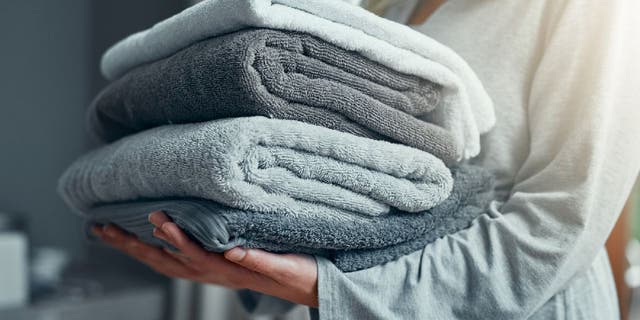 Closeup shot of an unrecognizable woman carrying a pile of towels while doing laundry at home