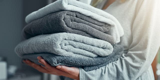 Closeup shot of an unrecognizable woman carrying a pile of towels while doing laundry at home