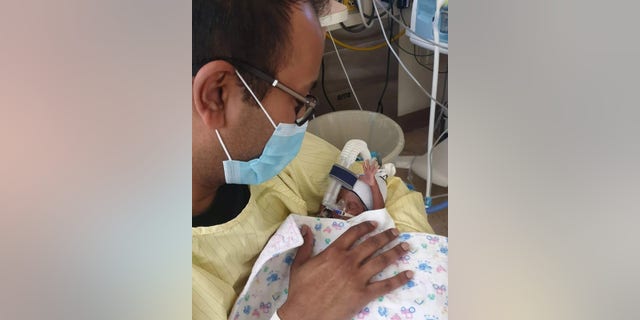 Father Kevin Nadarajah with child in NICU. (Courtesy: Shakina Rajendram)