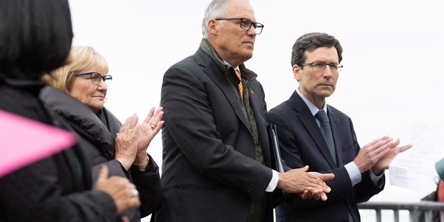 Washington Gov. Jay Inslee stands next to Attorney General Bob Ferguson