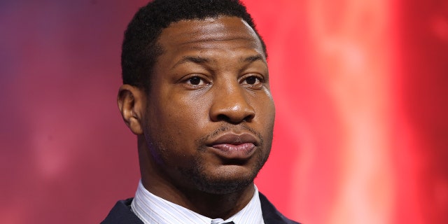 Jonathan Majors wears black suit.
