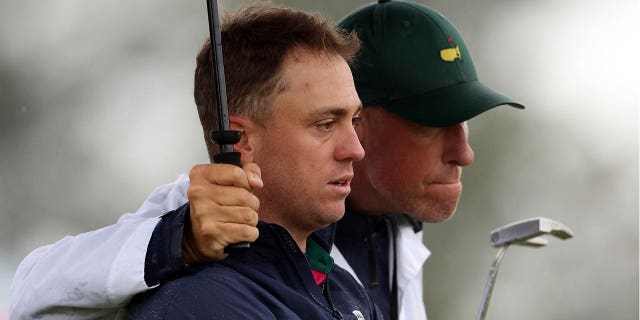 Justin Thomas of the United States and his jm "Bone" McKay responds to a bogey on the 18th green as the weather-delayed second round of the 2023 Masters resumes at Augusta National Golf Club on April 8, 2023 in Augusta, Ga.