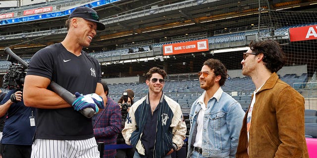 Aaron Judge, #99 of the New York Yankees, talks to Nick Jonas, Kevin Jonas and Joe Jonas before the game between the Philadelphia Phillies and the New York Yankees at Yankee Stadium on April 4, 2023 in New York.