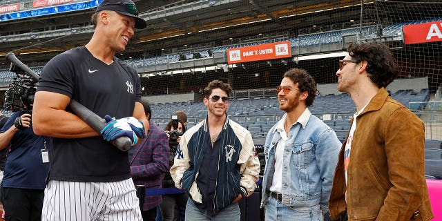 Aaron Judge, #99 of the New York Yankees, talks to Nick Jonas, Kevin Jonas and Joe Jonas before the game between the Philadelphia Phillies and the New York Yankees at Yankee Stadium on April 4, 2023 in New York.