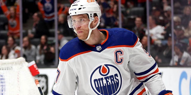 Connor McDavid #97 looks on after as assist to Ryan Nugent-Hopkins #93 of the Edmonton Oilers for an empty net goal during the third period of a game as Kevin Shattenkirk #22 of the Anaheim Ducks hits swings his stick in anger at Honda Center on April 05, 2023, in Anaheim, California.