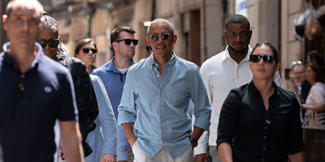 Barack and Michelle Obama walk through Barcelona streets with security