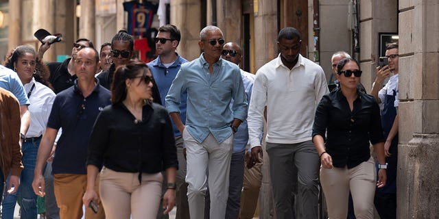 Barack and Michelle Obama walk through Barcelona streets with security