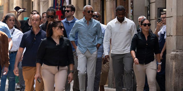 Barack and Michelle Obama walk through Barcelona streets with security