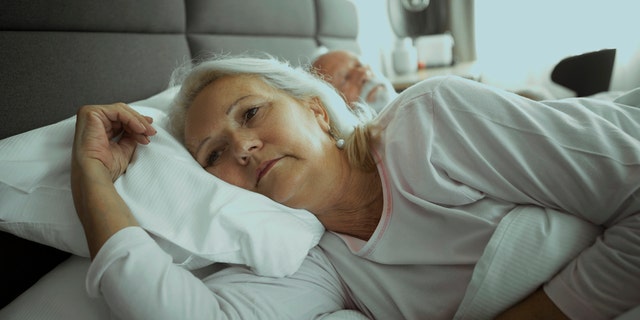 Older woman lying awake in bed