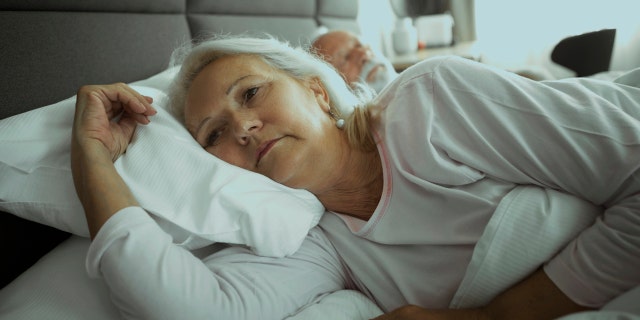 Older woman lying awake in bed