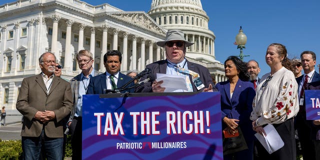 Morris Pearl wears hat and speaks at podium out front of the Capitol building