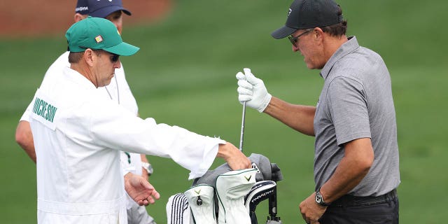 Phil Mickelson of the United States talks with his caddie Tim Mickelson warms up on the practice areaduring a practice round prior to the 2023 Masters Tournament at Augusta National Golf Club on April 4, 2023 in Augusta, Georgia.