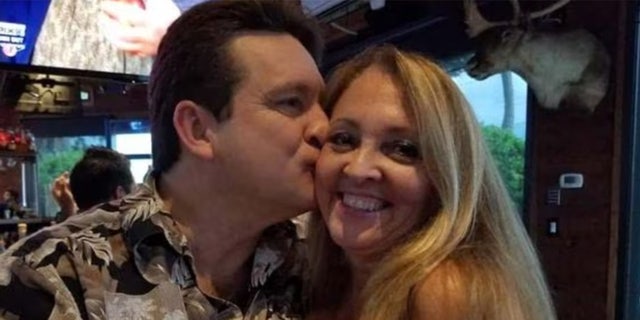 Randall Cooke kisses his wife, Kathy on the cheek in a restaurant.