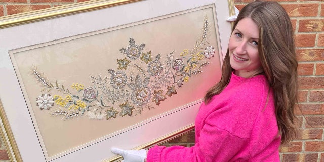 Isabel Murtough, manager of the Majesty and Monarchs auction, is pictured holding the cutting from Her Majesty's coronation gown. 