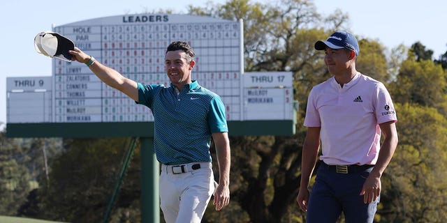 Rory McIlroy, left, and Colin Morikawa greet fans as they finish their round off the 18th green on April 10, 2022 at Augusta National Golf Club in Augusta, Ga. 
