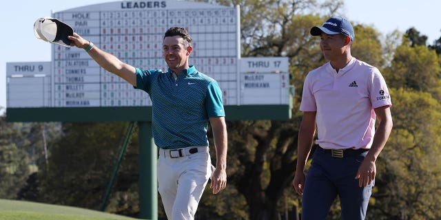 Rory McIlroy, left, and Colin Morikawa greet fans as they finish their round off the 18th green on April 10, 2022 at Augusta National Golf Club in Augusta, Ga.