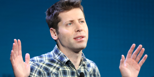 Sam Altman hands up speaking at event