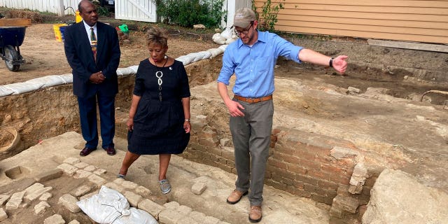 People stand at the brick-and-mortar foundation of one the oldest Black churches in the U.S. on Oct. 6, 2021, in Williamsburg, Virginia. Experts announced on April 6, 2023, that three men whose graves were found at the site were members of the church.