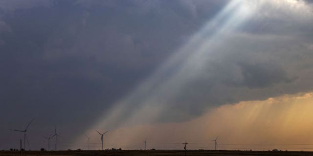 Sunlight filters through storm clouds onto a wind turbine as severe weather rolls through the Midwest on April 4, 2023, south of Stuart, Iowa. The rolling weather system hit Missouri with destructive tornadoes Wednesday morning.