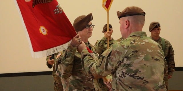Col. Meghann Sullivan in beret holding flag