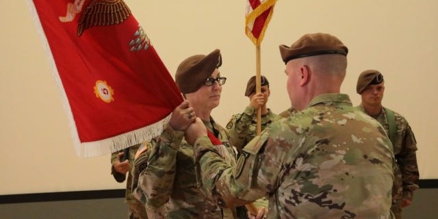 Col. Meghann Sullivan in beret holding flag