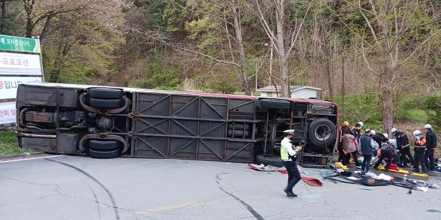 Emergency personnel rescue tourists after a bus fell on a road in Chungju, South Korea, on April 13, 2023. A 62-year-old woman died in the incident.