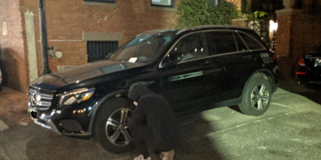 A climate activist deflates an SUV tire in Boston