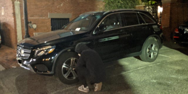 A climate activist deflates an SUV tire in Boston