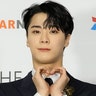 Moon Lim on the red carpet making a heart with both his hands and soft smiling for the camera