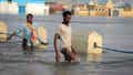 Men walk through floodwaters on a street in the town of Beledweyne, in Somalia Monday, May 15, 2023. Estimates from the UN Office for the Coordination of Humanitarian Affairs are that 460,000 people have been affected by flooding caused by heavy rains since mid-March. (AP Photo)