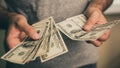 A man in a gray T-shirt holds dollars in his hands. Bank. Casino. Salary. Rates.