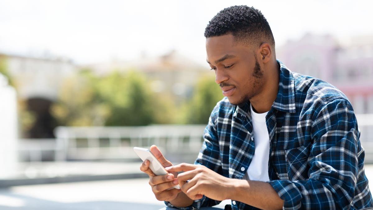 Man in flannel shirt, holding a phone